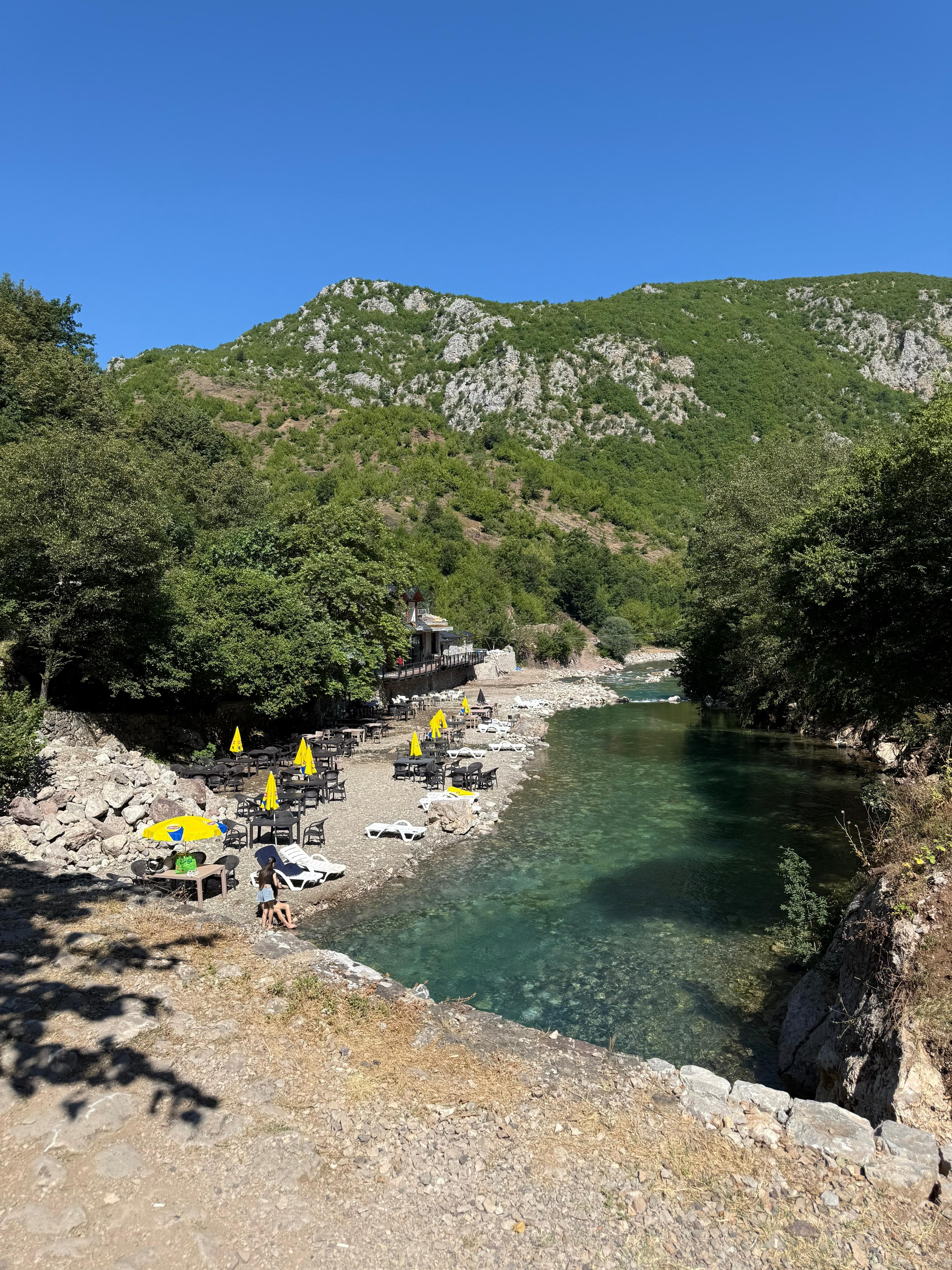 Turquoise Black Drin River with lounge chairs and umbrellas near Peshkopia, Albania
