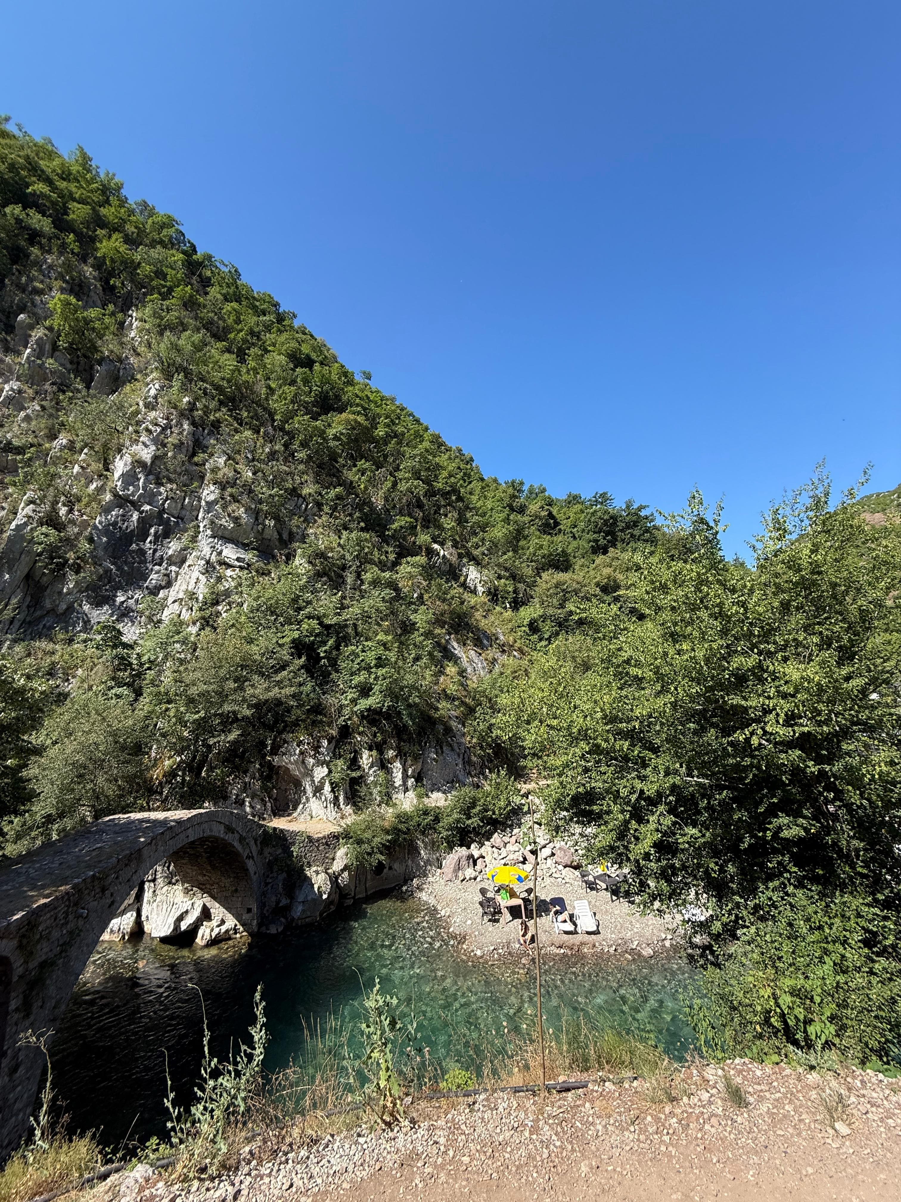 Ancient stone arch bridge over turquoise river in an Albanian canyon
